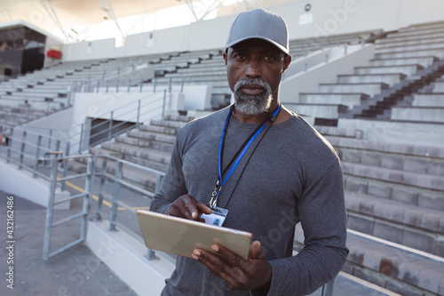 Portrait of african american male coach holding clipboard standing in the stadium photo