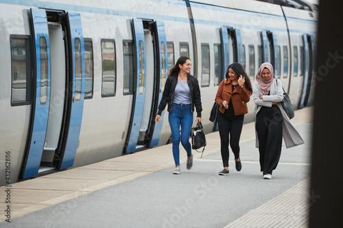 Smiling female friends at train station platform