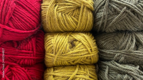 Red, olive color and yellow range of wool yarn. Multicolored skeins of wool close-up
