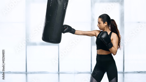 side view of focused sportswoman training with punching bag in gym. © LIGHTFIELD STUDIOS