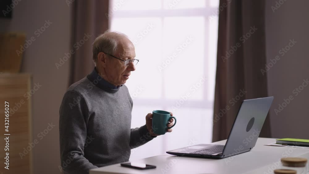 old man is communicating by video chat in laptop with friends or family, retiree is sitting alone at home kitchen, looking to web camera old man is communicating by video chat in laptop with friends or family, retiree is sitting alone at home kitchen, looking to web camera