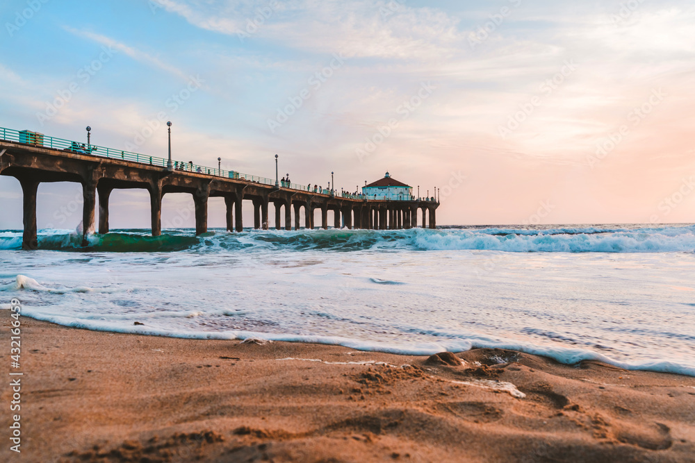 Manhattan beach pier at sunset, orange-pink sky with bright colors, beautiful landscape with ocean and sand