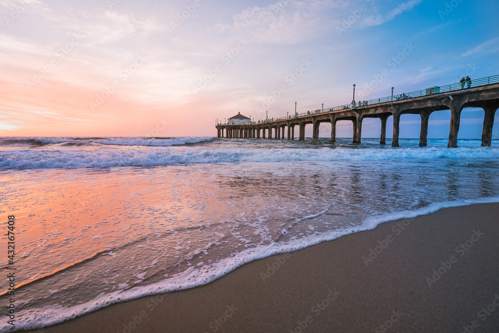 Manhattan beach pier at sunset, orange-pink sky with bright colors, beautiful landscape with ocean and sand