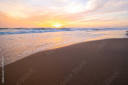 Beach in front of the ocean during sunset, calm ocean and beautiful colorful sky, California