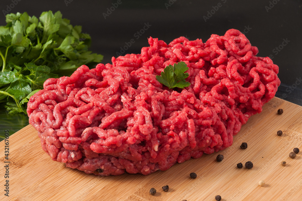 raw minced meat decorated with herbs on a wooden Board raw minced meat decorated with herbs on a wooden Board