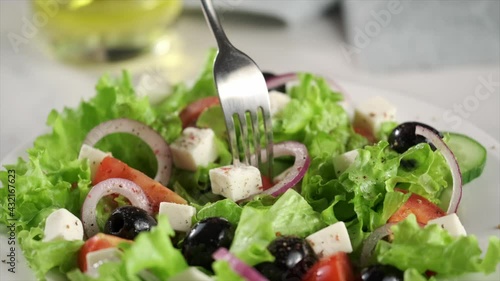 Vegetarian and organic food concept. Greek salad of fresh cucumber, tomato, lettuce, red onion, feta cheese and olives with olive oil. 
