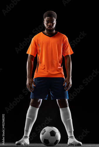 Portrait of young African soccer player posing isolated on black background. Concept of sport. © master1305