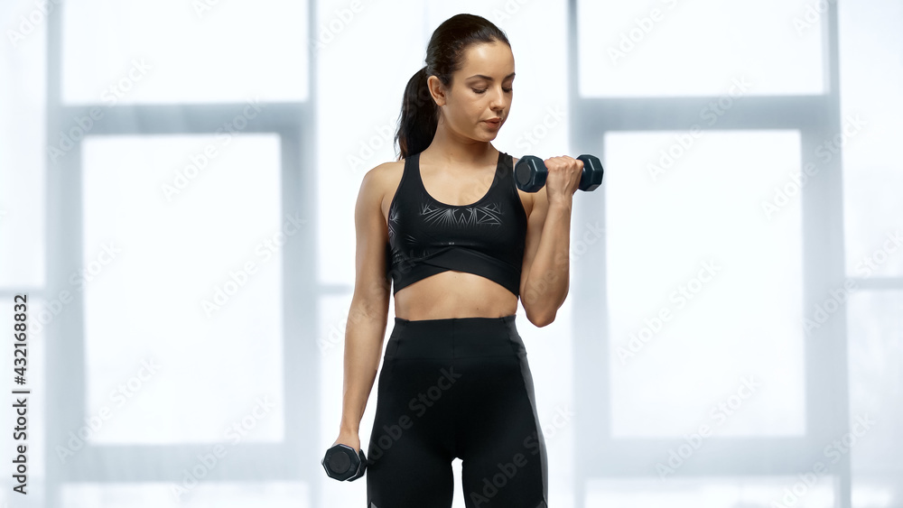 strong sportswoman in crop top working out with dumbbells. strong sportswoman in crop top working out with dumbbells.