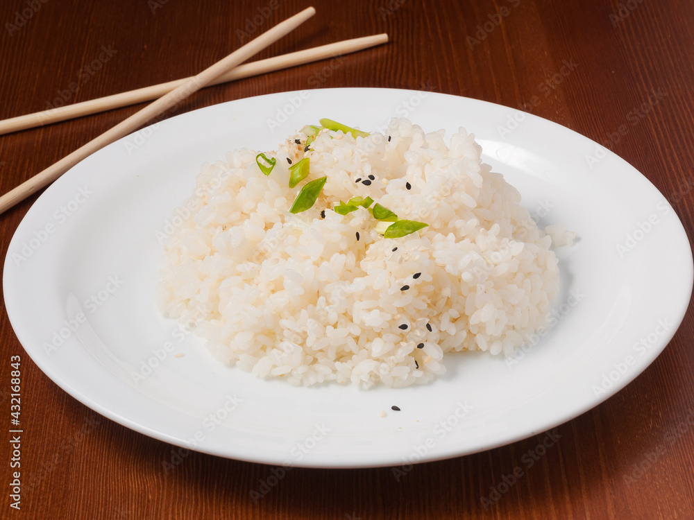 rice is garnished with green onions and sesame seeds on a white plate rice is garnished with green onions and sesame seeds on a white plate