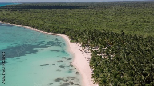 Crystal waters lap Palmilla white beach surrounded by lush vegetation, Dominican Republic. Aerial circling  photo