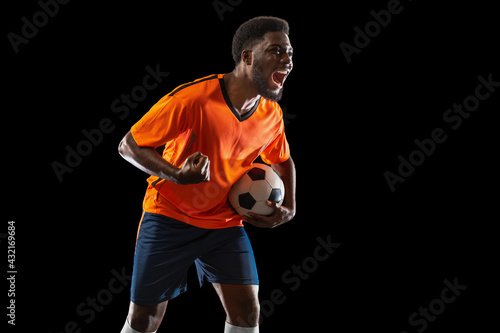 Portrait of young African soccer player posing isolated on black background. Concept of sport.