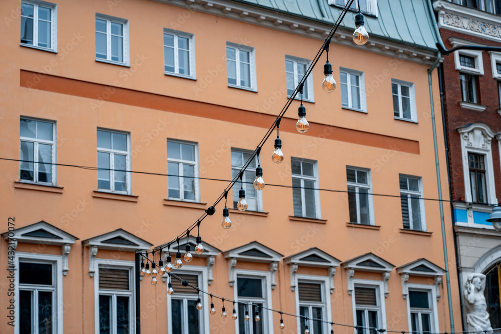 Many small bulbs hanging from a wire against the backdrop of a house in the center of the old town. Urban street lighting (765)
