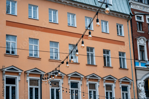 Many small bulbs hanging from a wire against the backdrop of a house in the center of the old town. Urban street lighting (765)