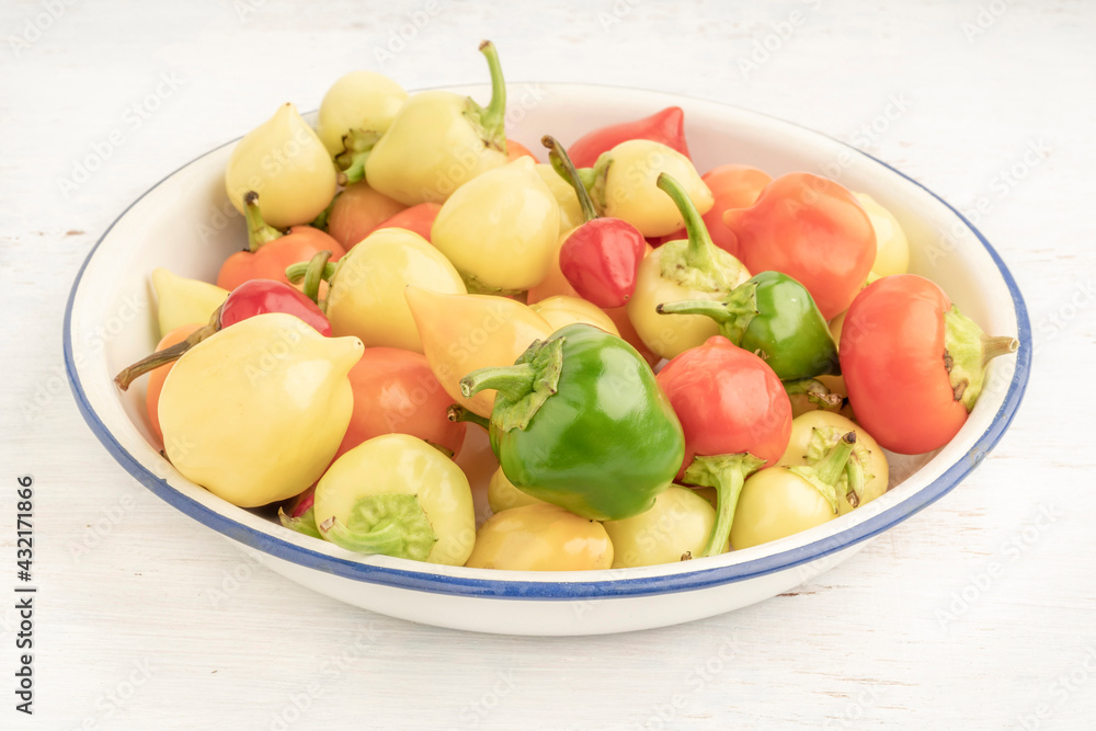 colorful hot peppers in a bowl on wooden table