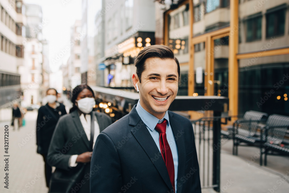Happy businessman social distancing with female colleagues on street in city Happy businessman social distancing with female colleagues on street in city