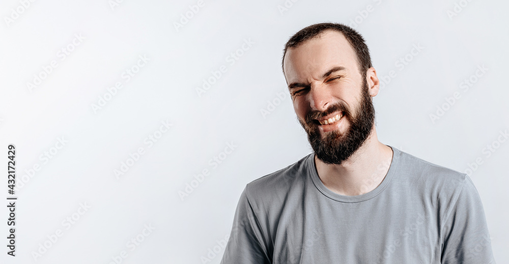 Handsome young brunette man frowning and closing eyes, angry on white background with space for advertising mock up Handsome young brunette man frowning and closing eyes, angry on white background with space for advertising mock up
