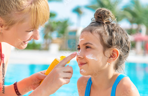 фотографія The child is smearing sunscreen on the mother. Selective focus.