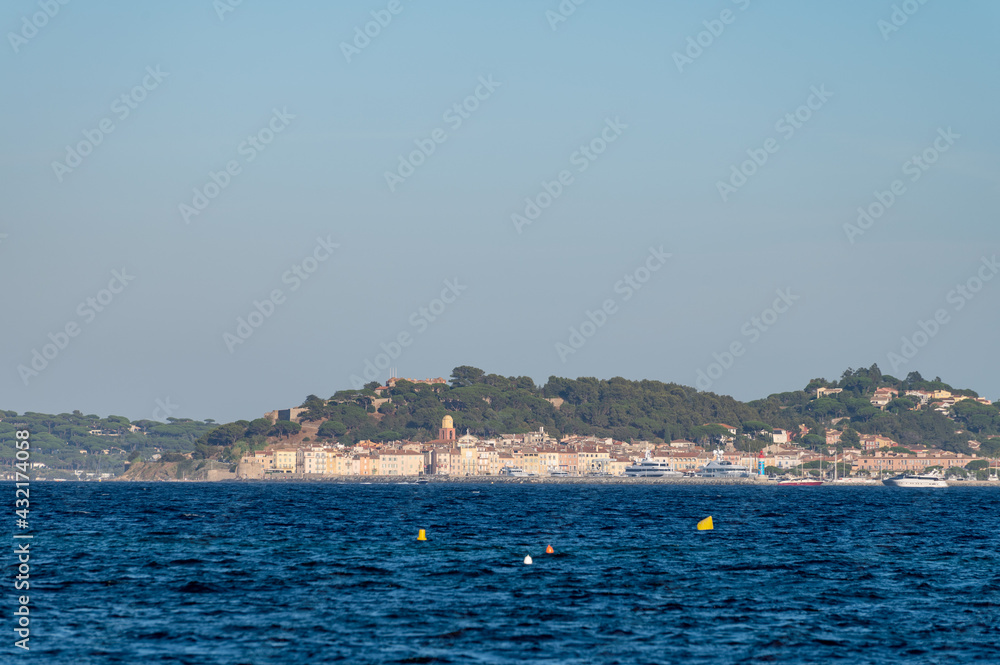 Blue water of Gulf of Saint-Tropez with outlines of Saint-Tropez town on background, French Riviera, France
