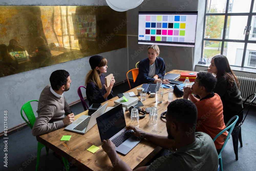 Female entrepreneur explaining strategy of product with colleagues at desk in conference room Female entrepreneur explaining strategy of product with colleagues at desk in conference room