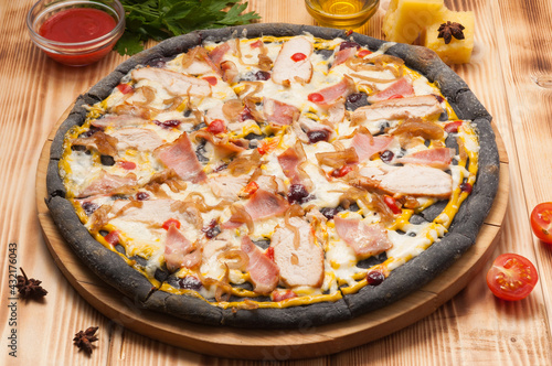 pizza with chicken bacon and onions on black dough