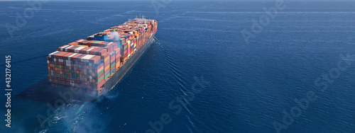 Aerial drone ultra wide photo above huge colourful container carrier vessel cruising deep blue open ocean sea