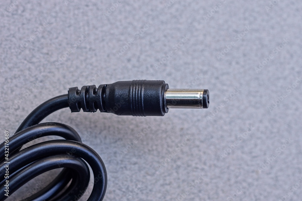 one metal plug on a black electrical wire on a gray table one metal plug on a black electrical wire on a gray table