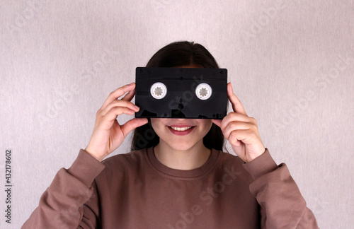Smiling girl with black old videotape. Videotape instead of eyes