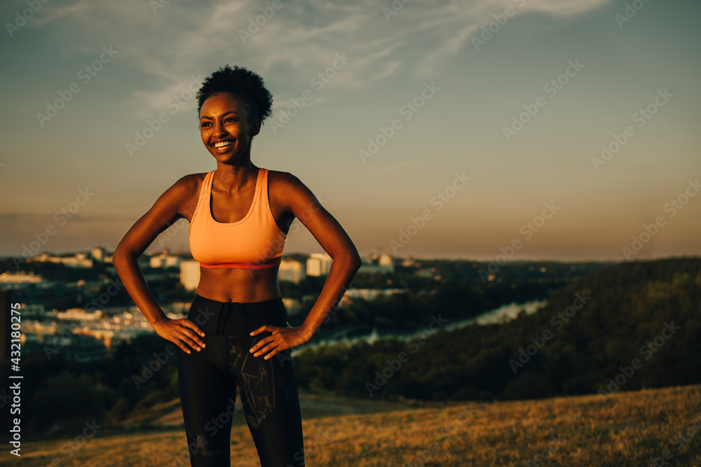 Smiling female athlete with hand on hip during sunset Smiling female athlete with hand on hip during sunset