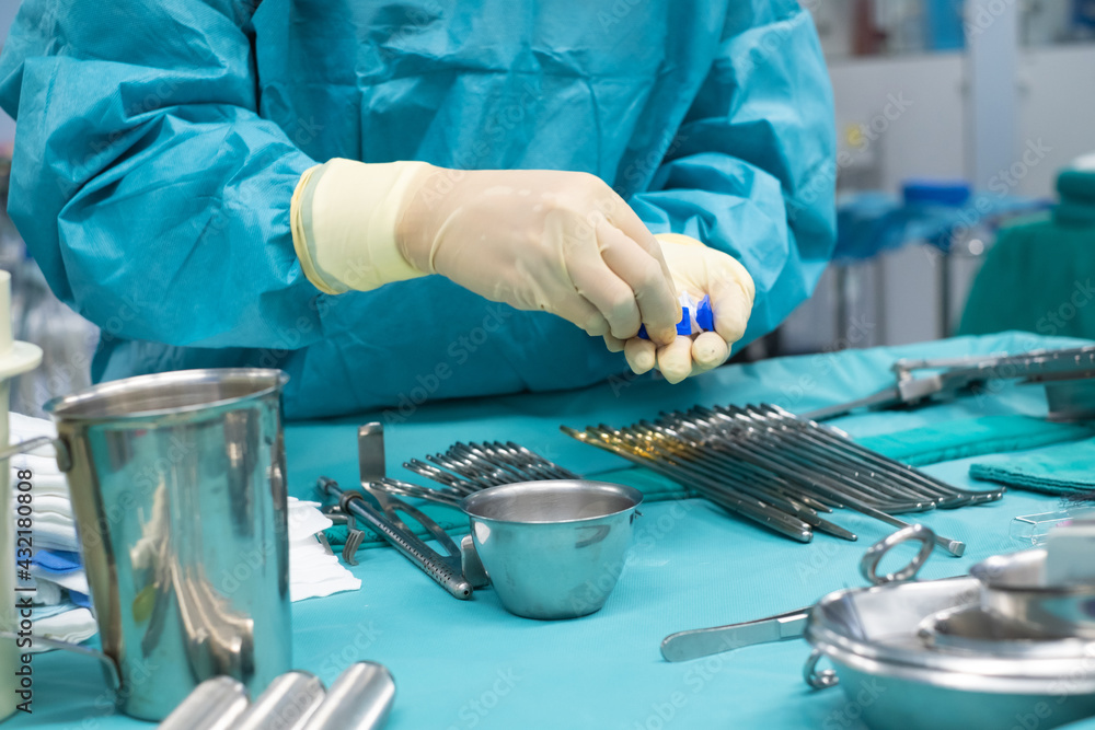 Medical team performing operation. Close up of scrub nurse taking medical instruments for operation. Medical and instrumentalist nurse working in an operating room with scissors of surgery. Medical team performing operation. Close up of scrub nurse taking medical instruments for operation. Medical and instrumentalist nurse working in an operating room with scissors of surgery.