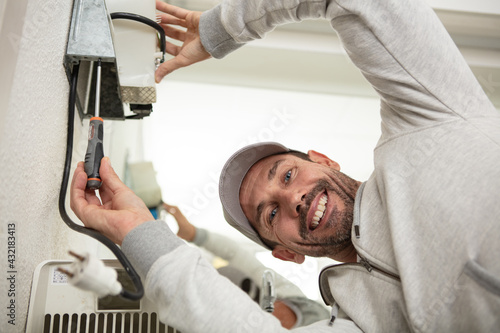 male technician repairing air conditioner unit
