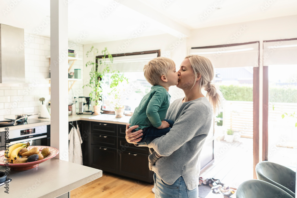 Mother and son kissing each other in kitchen at home Mother and son kissing each other in kitchen at home