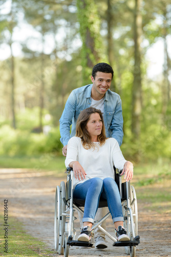 couple at wheelchair walk through the forest