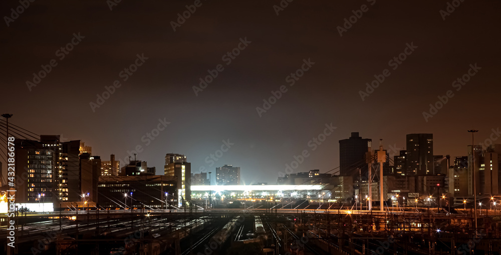 Naklejka premium Night time view of commuter trains under Nelson Mandela Bridge in Braamfontein Johannesburg CBD