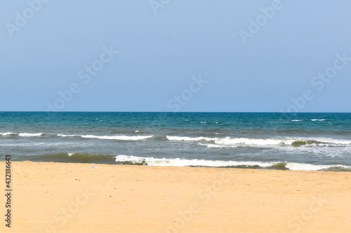 A beach with light blue sky , white sand and blue water