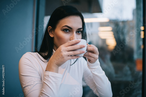 Focused woman drinking tasty coffee during break