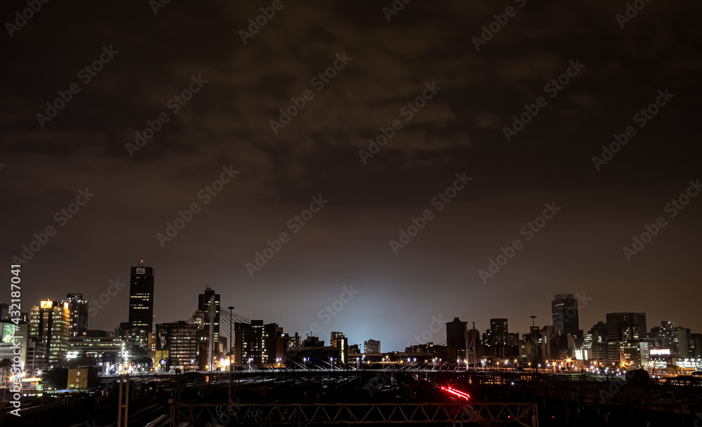 Naklejka premium Night time view of commuter trains under Nelson Mandela Bridge in Braamfontein Johannesburg CBD