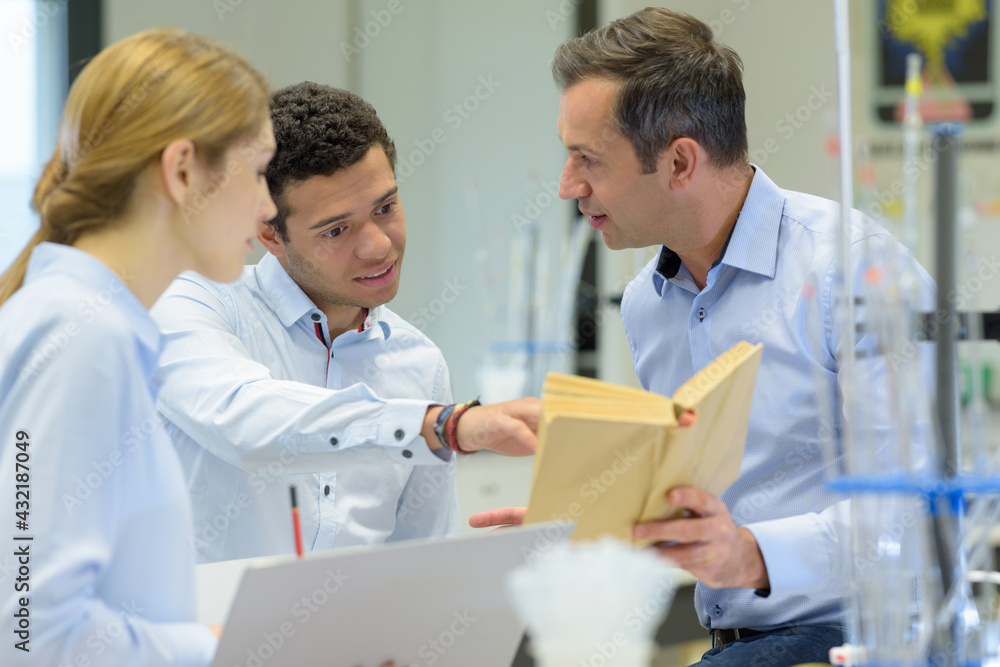 male student using pointing at book in science class male student using pointing at book in science class