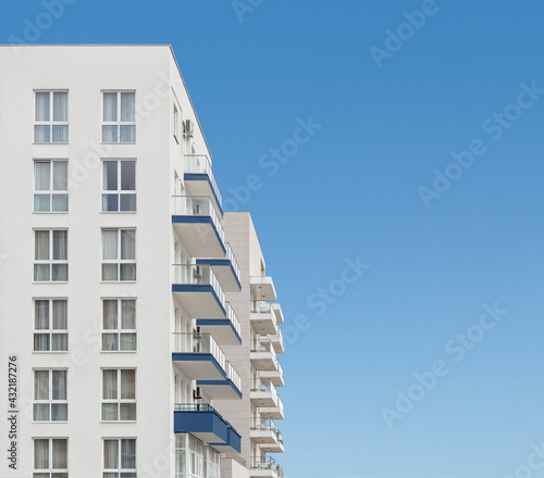 Apartment residential house or block of flats with balconies at clear blue sky background