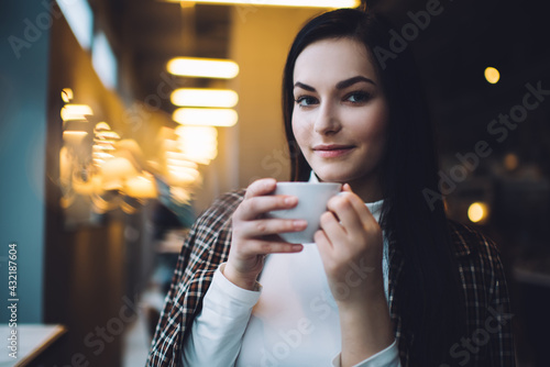 Happy young lady resting with cup of coffee in cafeteria