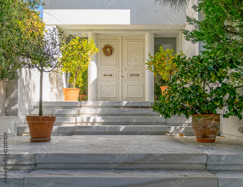 elegant white house facade and entrance door with potted plants, Athens Greece