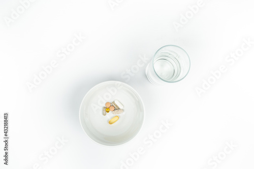 vitamins on a saucer and a glass of water. the need for vitamin supplements