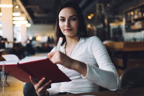 Thoughtful lady taking notes in cafe