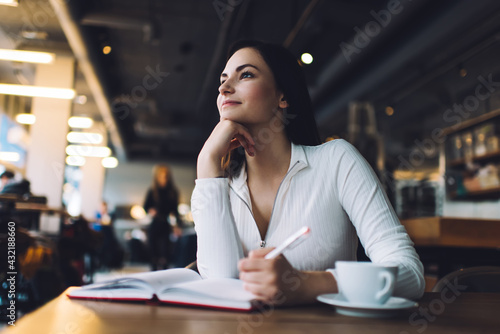 Dreamy woman with diary in cafe