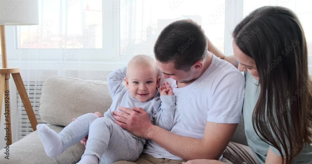 Cute baby boy having fun with parents sitting on sofa at home Cute baby boy having fun with parents sitting on sofa at home