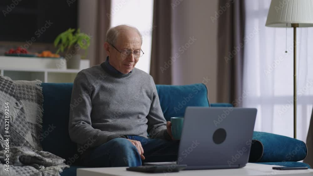 grandfather is sitting alone at home and communicating by video chat with friend or family, looking at web camera of laptop grandfather is sitting alone at home and communicating by video chat with friend or family, looking at web camera of laptop