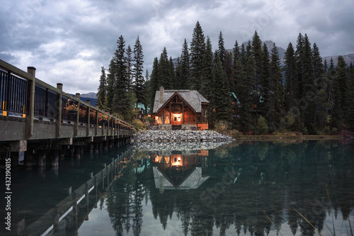 Wooden cottage glowing with pine forest and bridge reflection on Emerald lake at Yoho national park