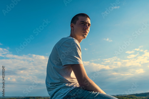 seated young man looks into the distance in a beautiful landscape