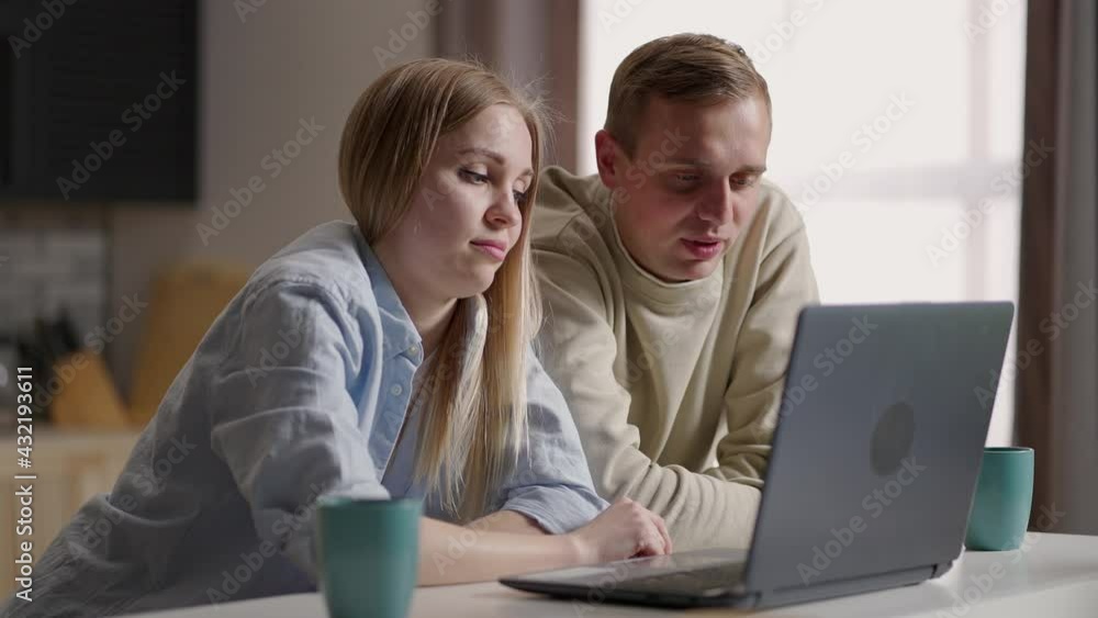 Married couple sit in kitchen making video call using internet and laptop device. Remote communication, pleasant videoconference conversation with family. Modern technology, apps usage concept Married couple sit in kitchen making video call using internet and laptop device. Remote communication, pleasant videoconference conversation with family. Modern technology, apps usage concept