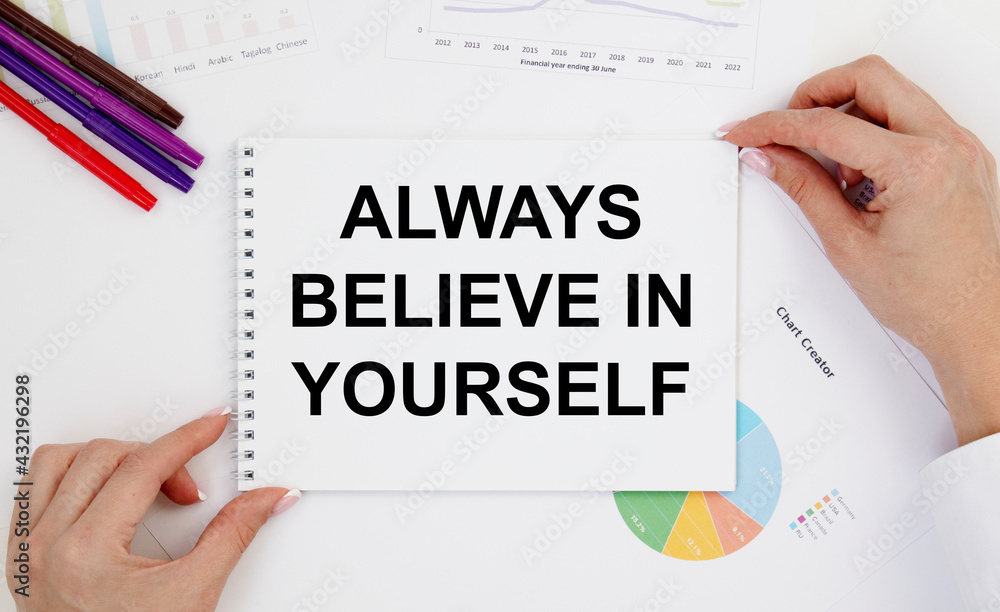 The girl with two hands holds a notebook with a tectonic always BELIEVE IN YOURSELF, next to pencils and diagrams. The girl with two hands holds a notebook with a tectonic always BELIEVE IN YOURSELF, next to pencils and diagrams.