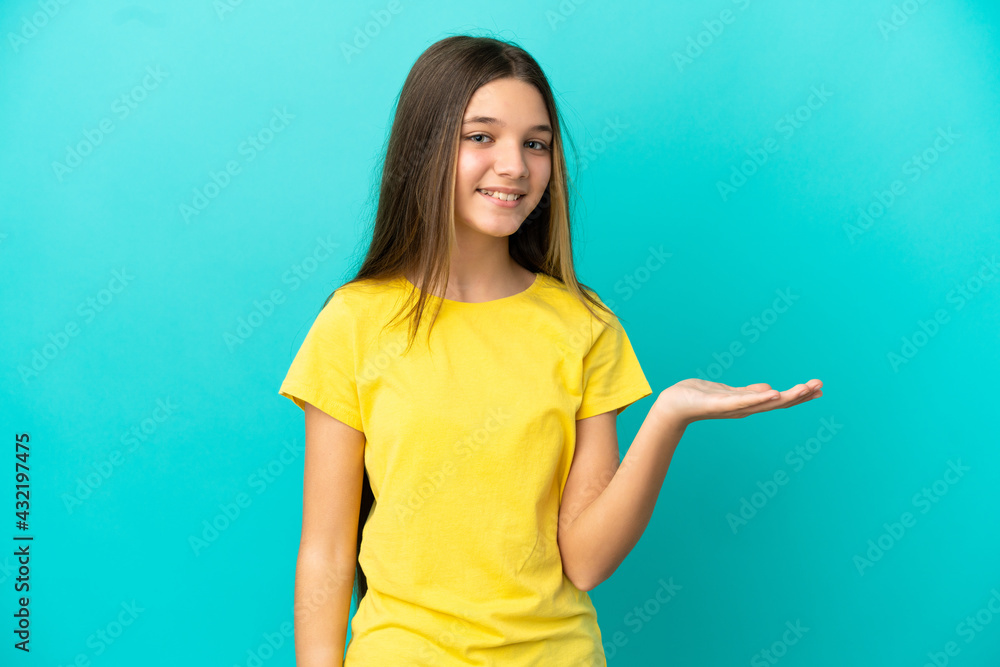 Little girl over isolated blue background presenting an idea while looking smiling towards
